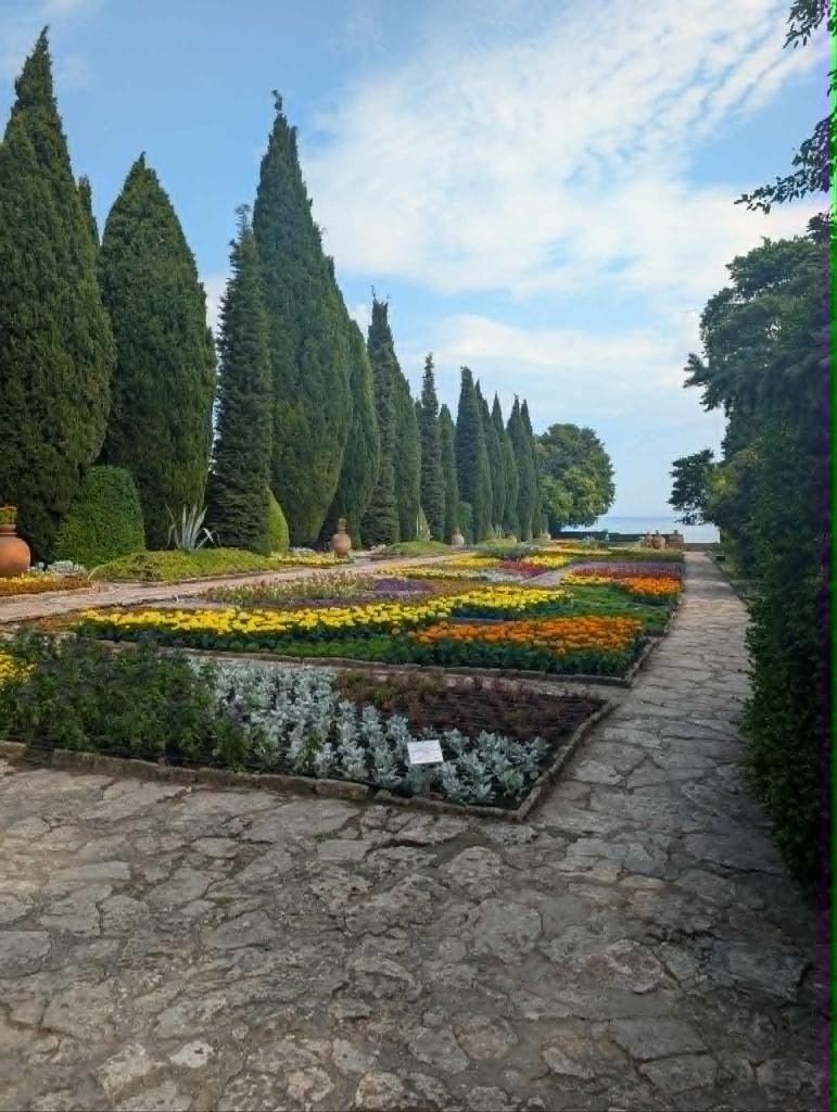 The lush botanical garden grounds at Balchik, with cypress trees and the Black Sea beyond.
